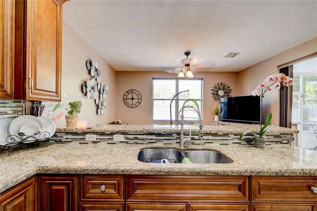 1100 SE 19th Ave, Homestead, FL 33035 - kitchen featuring backsplash, light stone countertops, and brown cabinets