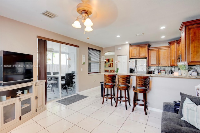1100 SE 19th Ave, Homestead, FL 33035 - kitchen featuring stainless steel fridge with ice dispenser, a peninsula, brown cabinetry, a kitchen bar, and recessed lighting
