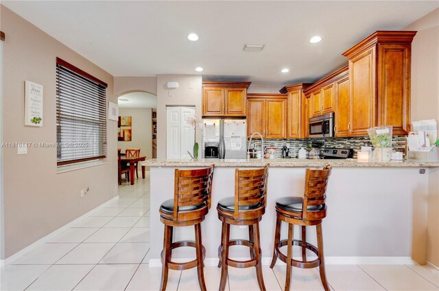 1100 SE 19th Ave, Homestead, FL 33035 - kitchen featuring appliances with stainless steel finishes, a peninsula, arched walkways, tasteful backsplash, and a breakfast bar