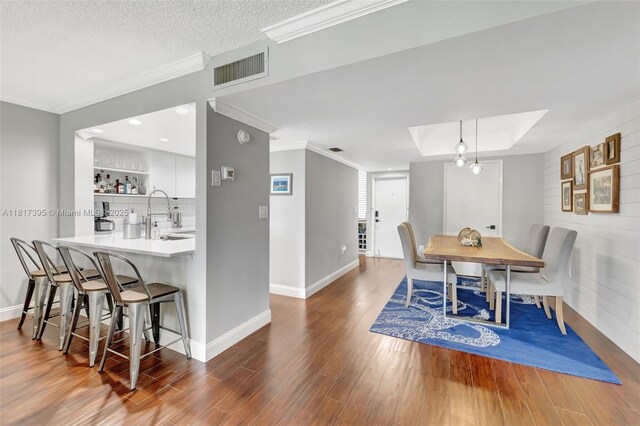 1100 SE 5th Ct Unit 87, Pompano Beach, FL 33060 - dining space featuring wood finished floors, crown molding, baseboards, a tray ceiling, and bar area