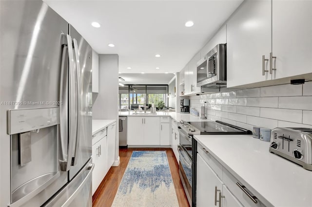 1100 SE 5th Ct Unit 87, Pompano Beach, FL 33060 - kitchen with stainless steel appliances, white cabinets, dark wood finished floors, tasteful backsplash, and light countertops