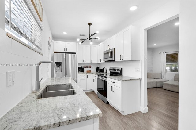 1013 S 24th Ave, Hollywood, FL 33020 - kitchen featuring stainless steel appliances, a sink, a chandelier, light wood finished floors, and white cabinetry