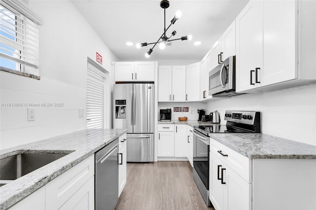 1013 S 24th Ave, Hollywood, FL 33020 - kitchen featuring stainless steel appliances, a chandelier, white cabinets, light wood-type flooring, and light stone counters