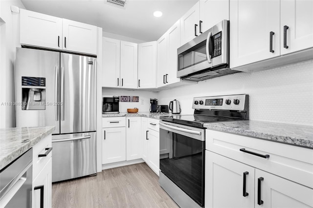 1013 S 24th Ave, Hollywood, FL 33020 - kitchen featuring stainless steel appliances, white cabinets, light stone counters, light wood-style flooring, and recessed lighting