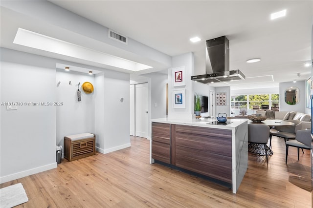 9310 Sunrise Lakes Blvd Unit 206, Sunrise, FL 33322 - kitchen featuring wall chimney range hood, light countertops, light wood finished floors, and open floor plan