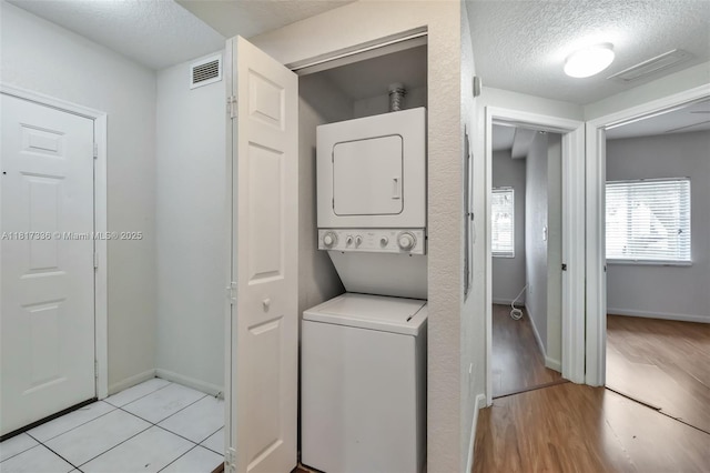 1103 Golden Lakes Blvd Unit 1013, West Palm Beach, FL 33411 - laundry area with stacked washer / dryer, a textured ceiling, light wood-type flooring, and baseboards