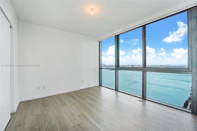 3131 NE 7th Ave Unit 3101, Miami, FL 33137 - empty room featuring floor to ceiling windows, wood finished floors, baseboards, and a water view