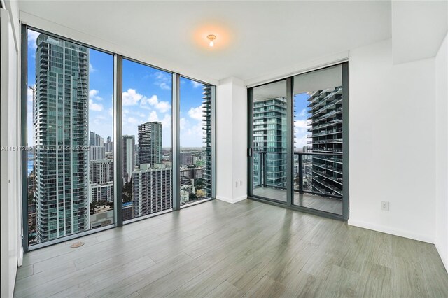 3131 NE 7th Ave Unit 3101, Miami, FL 33137 - unfurnished room with expansive windows, wood finished floors, a city view, and baseboards