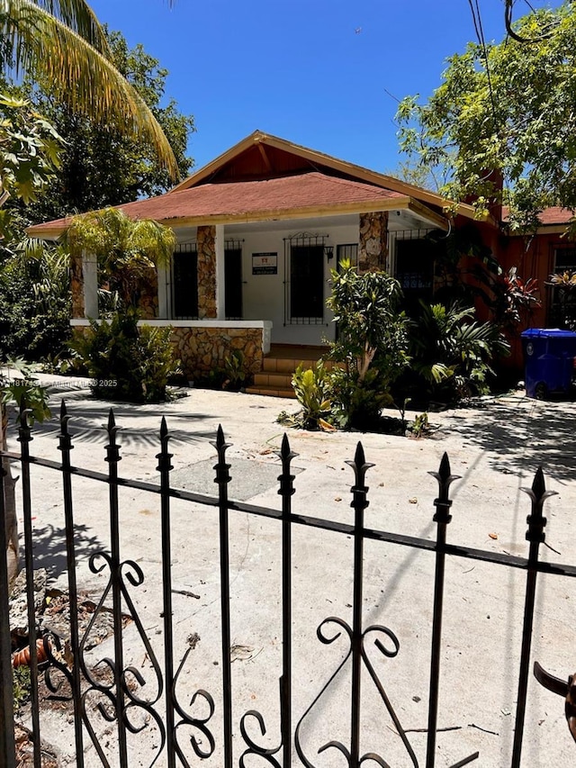 1262 SW 4th St, Miami, FL 33135 - ranch-style home featuring a porch, a fenced front yard, and stone siding