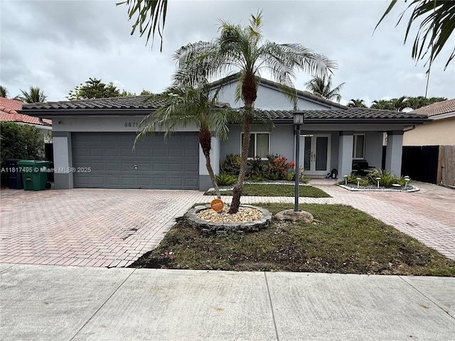 6871 SW 159th Pl, Miami, FL 33193 - view of front of property featuring french doors, decorative driveway, a garage, stucco siding, and a tile roof