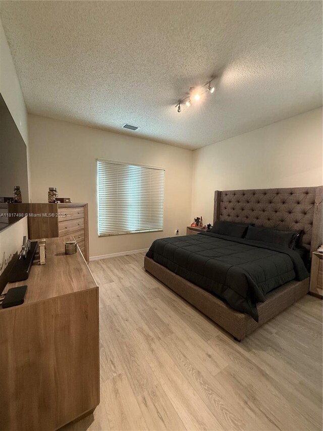 2046 NE 4th Ct, Homestead, FL 33033 - bedroom with light wood-type flooring, a textured ceiling, and track lighting