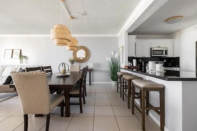 5601 Collins Ave Unit 923, Miami Beach, FL 33140 - dining area with a textured ceiling, light tile patterned floors, ornamental molding, and baseboards