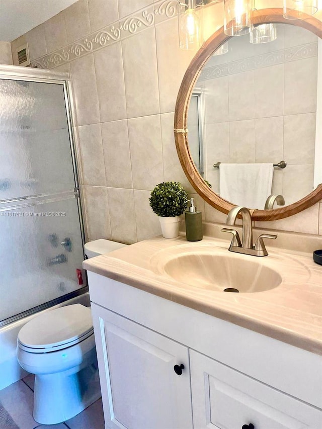 5601 Collins Ave Unit 923, Miami Beach, FL 33140 - bathroom with tile walls, vanity, toilet, combined bath / shower with glass door, and decorative backsplash