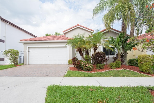 5402 NW 110th Ave, Doral, FL 33178 - mediterranean / spanish-style home featuring decorative driveway, a garage, a tiled roof, and stucco siding
