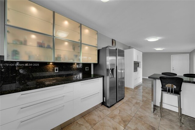 11020 SW 55th St, Miami, FL 33165 - kitchen with stainless steel fridge with ice dispenser, backsplash, dark stone countertops, white cabinets, and glass insert cabinets