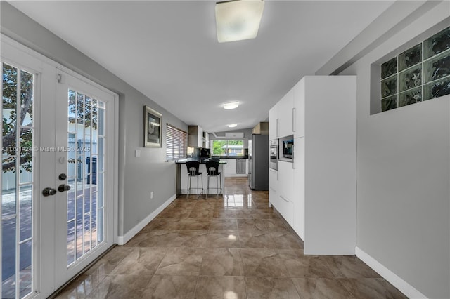 11020 SW 55th St, Miami, FL 33165 - kitchen with freestanding refrigerator, a peninsula, a kitchen bar, white cabinets, and baseboards