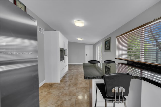 11020 SW 55th St, Miami, FL 33165 - kitchen featuring freestanding refrigerator, white cabinets, black oven, a kitchen bar, and baseboards