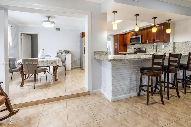 7968 Venetian St, Miramar, FL 33023 - kitchen with stainless steel appliances, backsplash, ornamental molding, a peninsula, and light stone counters