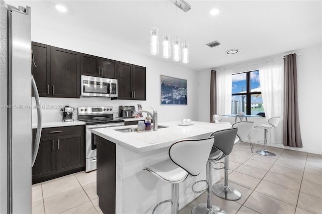 10225 SW 231st Ln, Miami, FL 33190 - kitchen with stainless steel appliances, a sink, light tile patterned floors, a breakfast bar, and hanging light fixtures