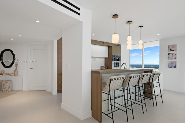 450 Alton Rd Unit 2007, Miami Beach, FL 33139 - kitchen with a kitchen breakfast bar, white cabinetry, a sink, modern cabinets, and decorative light fixtures