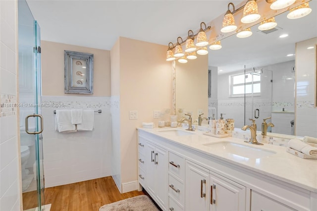200 Wrenn St Ph 701, Plantation Key, FL 33070 - full bathroom featuring double vanity, wood finished floors, a shower stall, tile walls, and a wainscoted wall