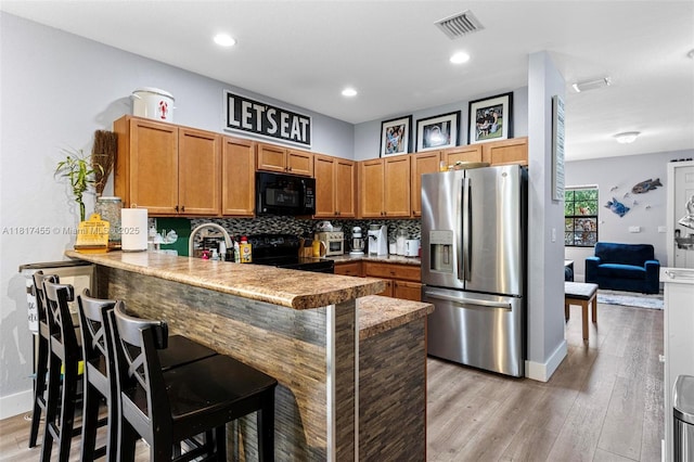 22791 SW 88th Pl, Cutler Bay, FL 33190 - kitchen featuring black appliances, a peninsula, baseboards, light wood-style flooring, and backsplash