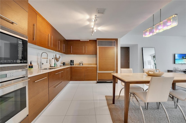 485 Brickell Ave Unit 1801, Miami, FL 33131 - kitchen with stainless steel appliances, light countertops, brown cabinetry, and light tile patterned flooring