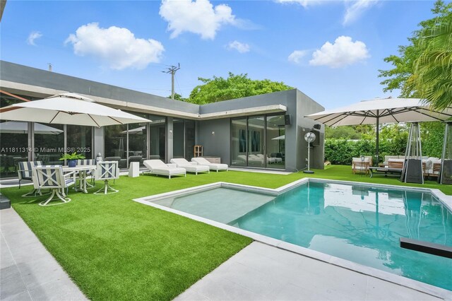 1845 NE 124th St, North Miami, FL 33181 - rear view of house with outdoor lounge area, an outdoor pool, a yard, and a patio
