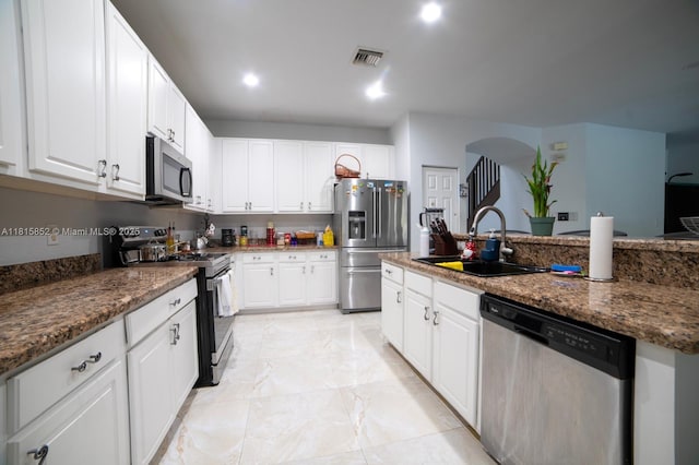 4452 Rainbow Ave, Weston, FL 33332 - kitchen with stainless steel appliances, arched walkways, white cabinetry, light marble finish floors, and recessed lighting