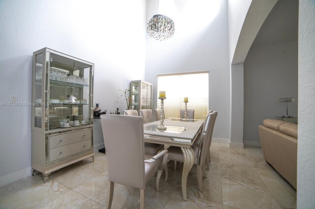 4452 Rainbow Ave, Weston, FL 33332 - dining room featuring light marble finish flooring, a high ceiling, and a chandelier