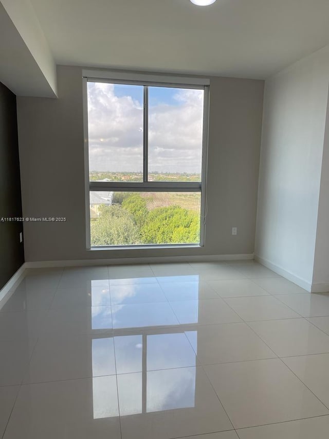 7661 NW 107th Ave Unit 614, Doral, FL 33178 - tiled spare room featuring plenty of natural light and baseboards