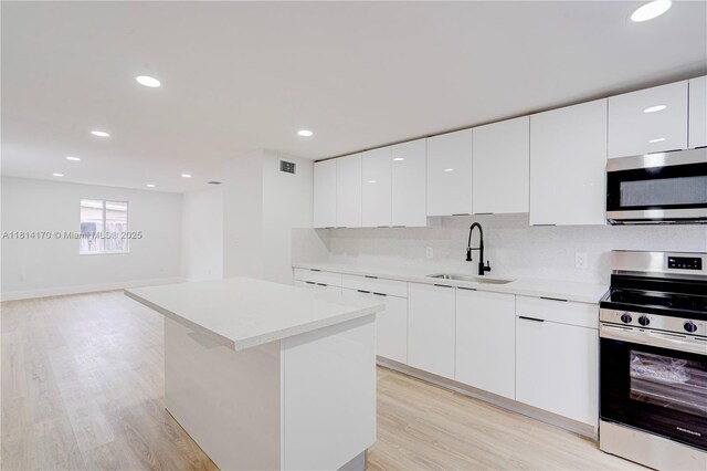 6044 SW 37th St, Miramar, FL 33023 - kitchen featuring stainless steel appliances, a sink, modern cabinets, light wood finished floors, and recessed lighting