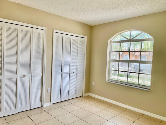 14610 SW 170th Ter, Miami, FL 33177 - unfurnished bedroom featuring two closets, a textured ceiling, light tile patterned floors, and baseboards