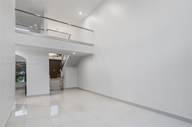 4425 NW 93rd Doral Ct, Doral, FL 33178 - unfurnished bedroom with arched walkways, baseboards, a towering ceiling, tile patterned flooring, and recessed lighting