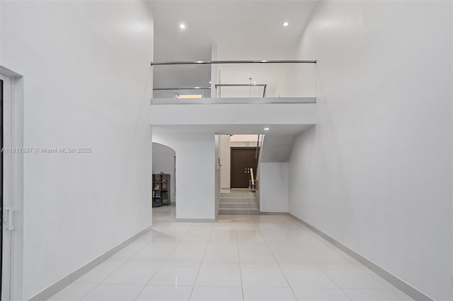 4425 NW 93rd Doral Ct, Doral, FL 33178 - staircase with arched walkways, baseboards, tile patterned floors, a towering ceiling, and recessed lighting