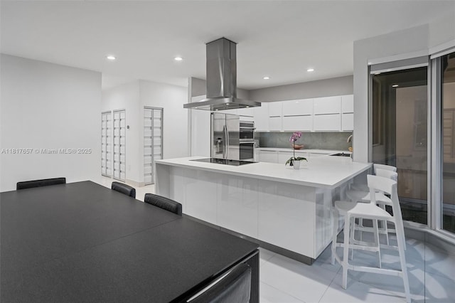 4425 NW 93rd Doral Ct, Doral, FL 33178 - kitchen with island exhaust hood, modern cabinets, a breakfast bar, white cabinetry, and appliances with stainless steel finishes