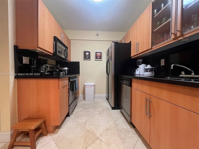 100 Lincoln Rd Unit 848, Miami Beach, FL 33139 - kitchen featuring appliances with stainless steel finishes, dark countertops, glass insert cabinets, baseboards, and light marble finish flooring