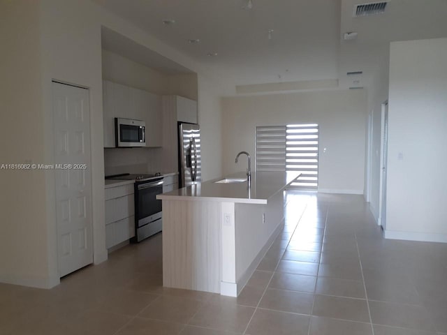8055 NW 104th Ave Unit 32, Doral, FL 33178 - kitchen featuring appliances with stainless steel finishes, modern cabinets, a sink, a kitchen island with sink, and light tile patterned floors