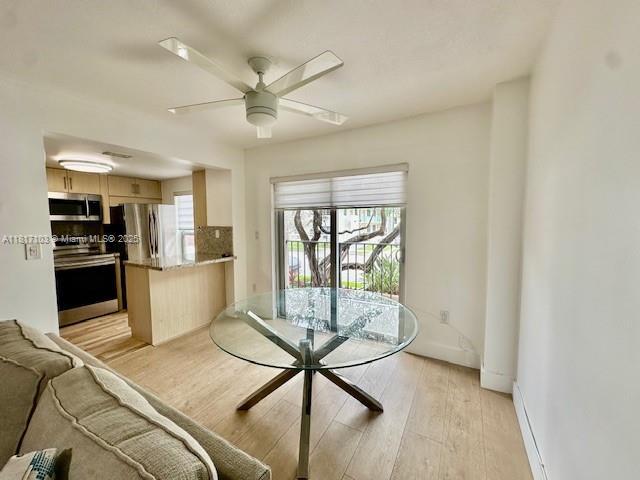 110 Salamanca Ave Unit 207, Coral Gables, FL 33134 - dining space with light wood-type flooring, a ceiling fan, a baseboard radiator, and baseboards