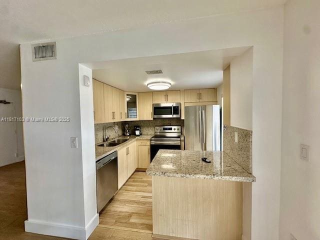 110 Salamanca Ave Unit 207, Coral Gables, FL 33134 - kitchen featuring appliances with stainless steel finishes, light brown cabinets, backsplash, light stone countertops, and light wood finished floors