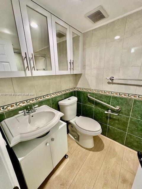 110 Salamanca Ave Unit 207, Coral Gables, FL 33134 - bathroom featuring tile walls, vanity, toilet, and wood finished floors