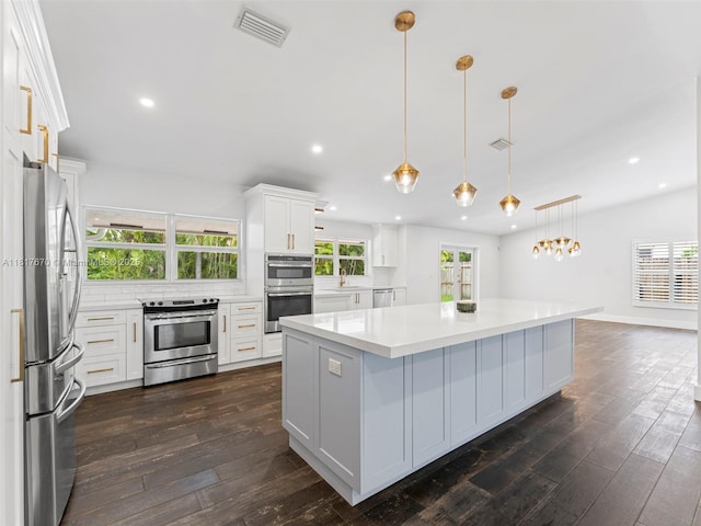 5976 SW 88th Pl, Miami, FL 33173 - kitchen with appliances with stainless steel finishes, a center island, white cabinetry, light countertops, and dark wood finished floors