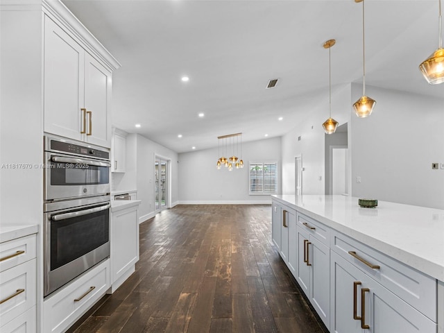 5976 SW 88th Pl, Miami, FL 33173 - kitchen featuring stainless steel double oven, dark wood finished floors, light countertops, white cabinets, and hanging light fixtures