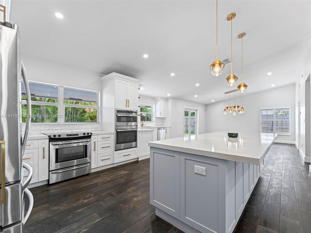 5976 SW 88th Pl, Miami, FL 33173 - kitchen featuring appliances with stainless steel finishes, dark wood-style flooring, a center island, light countertops, and decorative backsplash
