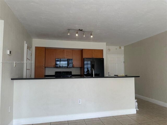 10350 W Bay Harbor Dr Unit 4F, Bay Harbor Islands, FL 33154 - kitchen with black appliances, dark countertops, brown cabinetry, light tile patterned floors, and a textured ceiling