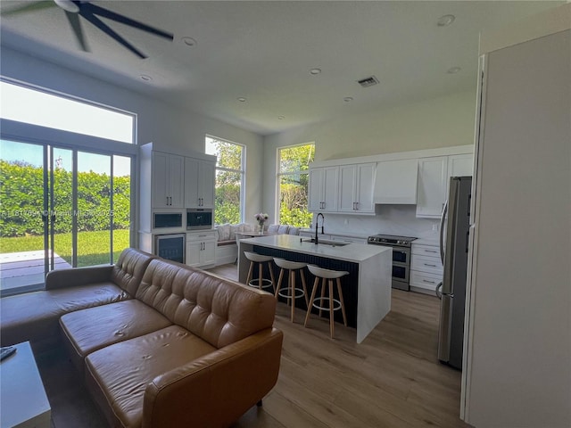 7714 NW 70th Way, Parkland, FL 33067 - kitchen with open floor plan, stainless steel appliances, custom exhaust hood, light countertops, and light wood-style floors