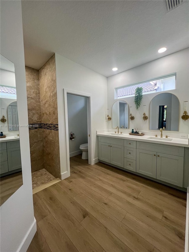 7714 NW 70th Way, Parkland, FL 33067 - bathroom with wood finished floors, double vanity, a walk in shower, and recessed lighting