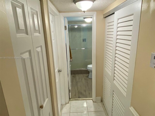 6200 NW 44th St Unit 115, Lauderhill, FL 33319 - bathroom with a closet, a textured ceiling, toilet, a shower stall, and tile patterned floors