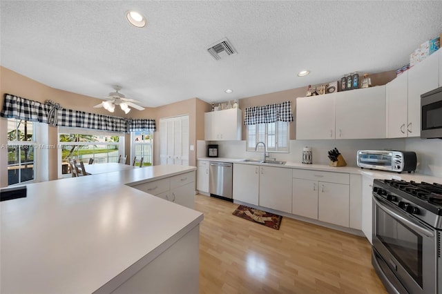 13344 NW 7th St, Plantation, FL 33325 - kitchen featuring appliances with stainless steel finishes, a sink, light countertops, light wood-style flooring, and a textured ceiling