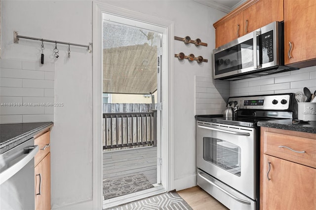 1636 Arthur St, Hollywood, FL 33020 - kitchen with stainless steel appliances, dark countertops, decorative backsplash, brown cabinetry, and ornamental molding